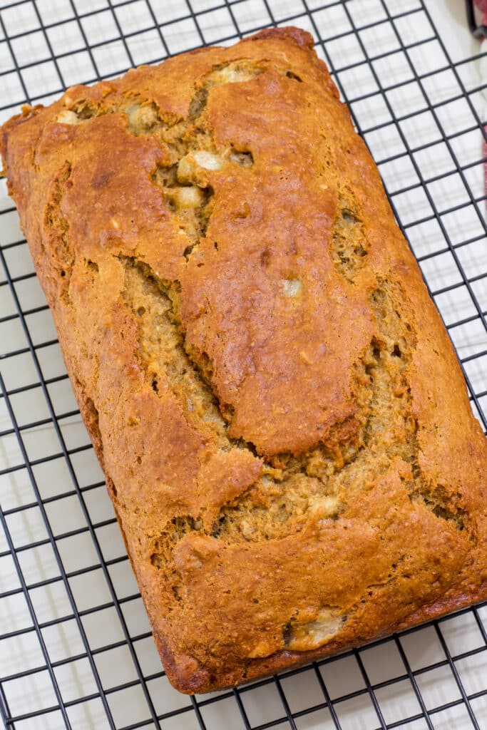 The entire loaf of healthier banana bread on a black cooling rack, it is not cut.