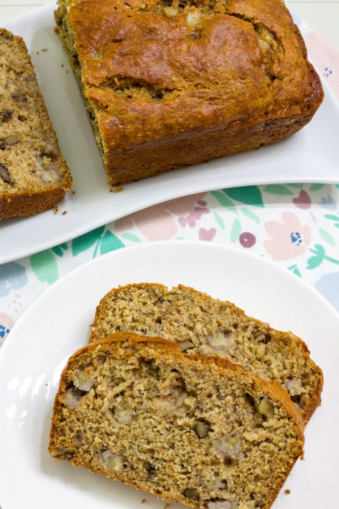 A cut loaf of banana bread at the top of the image and two slices on a plate in the bottom of the image.