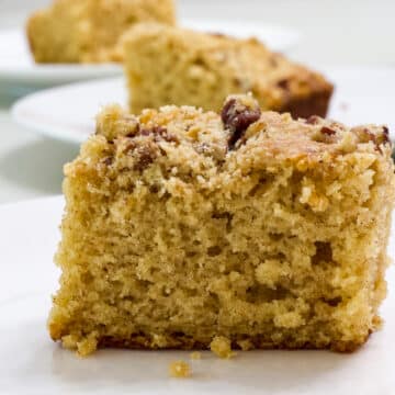 Close up side view of one piece of cowboy coffee cake on a white plate.