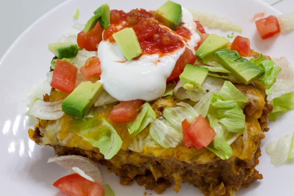 Overhead shot of one serving of taco salad casserole with toppings.