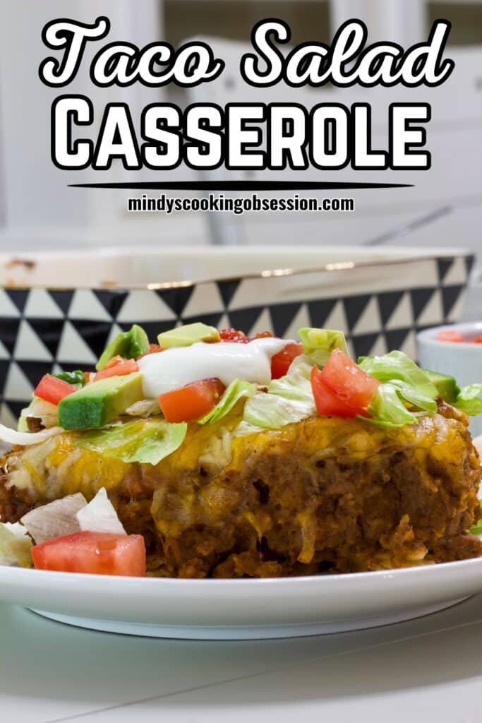 One serving of taco salad casserole with toppings, the recipe title is in text at the top of the image.