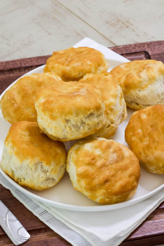 A plate with several biscuits on it sitting on a wooden serving tray.