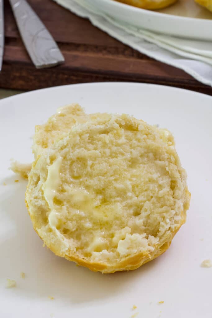 A cut biscuit showing the inside that has butter on it.