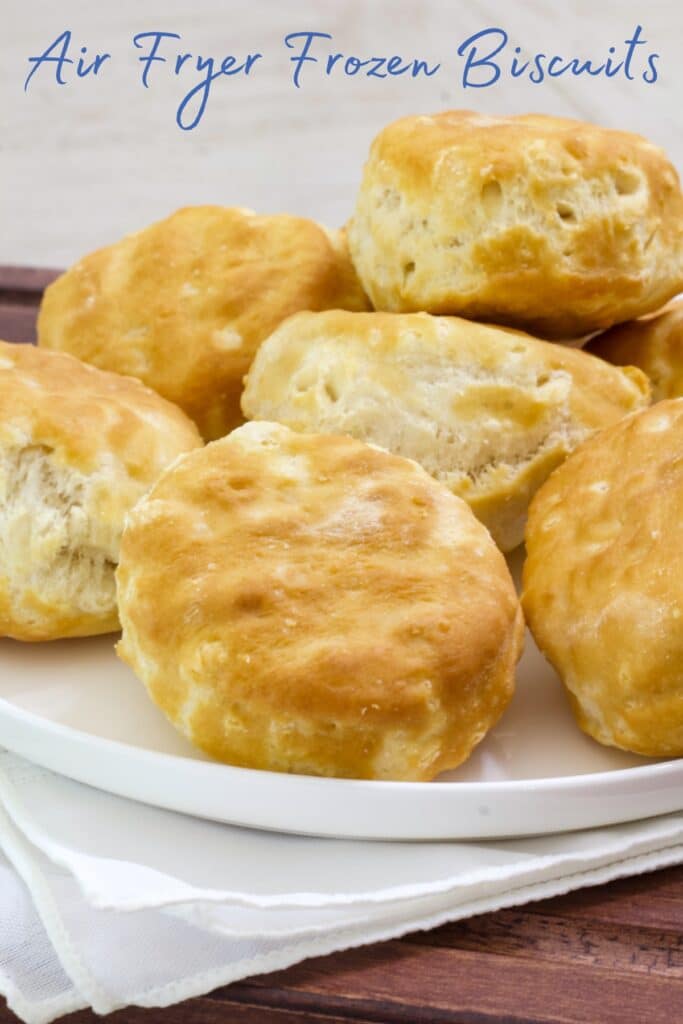 A plate of biscuits with the words air fryer frozen biscuits at the top of the image in text.