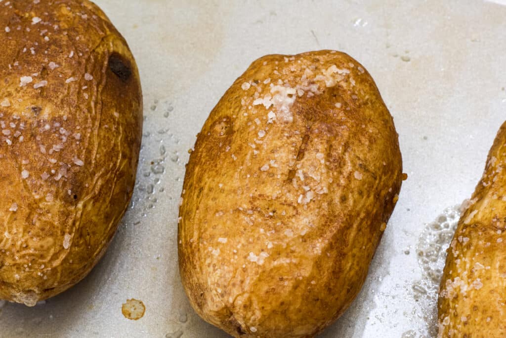 Close up view of baked potatoes on a sheet pan after they have been cooked.