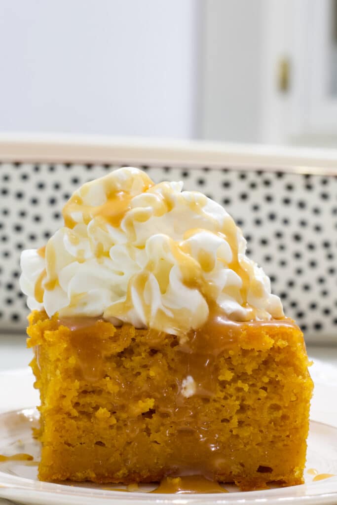 A piece of pumpkin pie cake with caramel sauce and whipped topping on it.