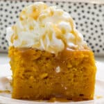 One piece of pumpkin pie cake topped with whipped cream and caramel topping.