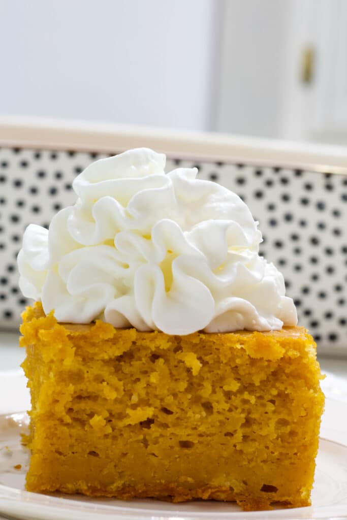 A piece of pumpkin pie cake topped with whipped topping.