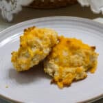 Two baked Easy Garlic & Cheddar Cheese Drop Biscuits sitting on a plate.