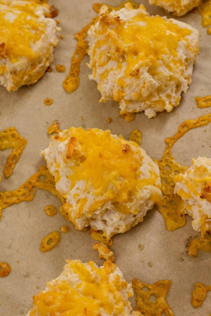 Close up of the baked Garlic & Cheddar Cheese Drop Biscuits on a parchment lined baking tray.