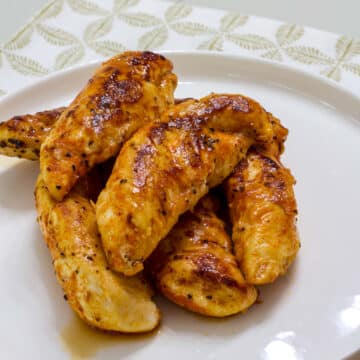 Several Pan Fried Chicken Tenders on a white plate.