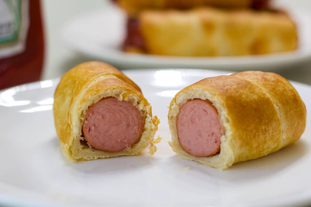 One Air Fryer Pigs in a Blanket that has been cut open so the inside is visible.
