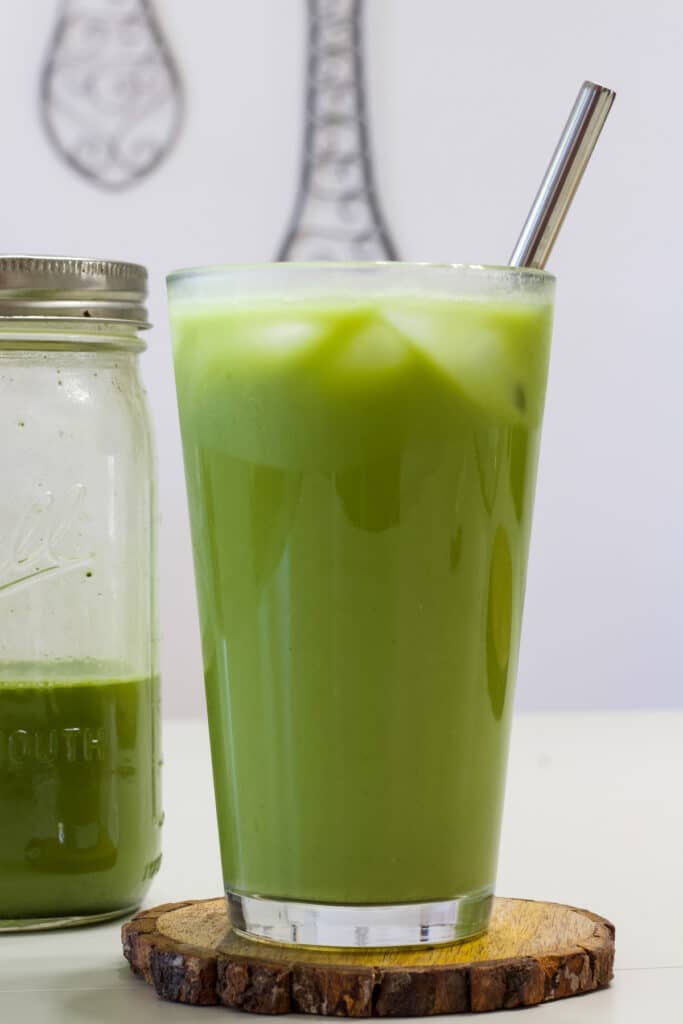 One tall glass of Copycat Starbucks Iced Pineapple Matcha Drink and a mason jar next to it with a drink ready to go in a glass.