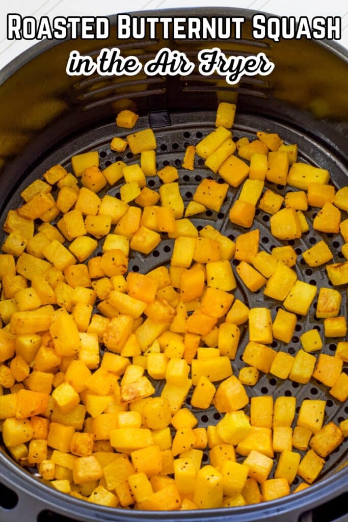 An air fryer basket full of butternut squash that has been cooked, the recipe title is in text above it.