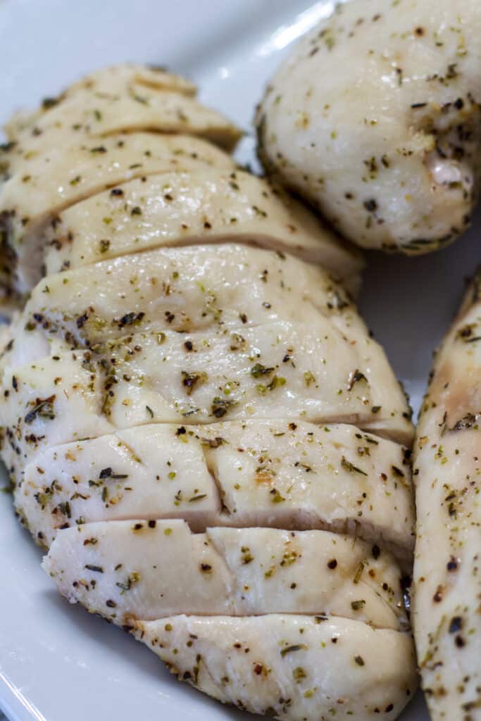 One slice oven baked chicken breast sliced on a white plate.