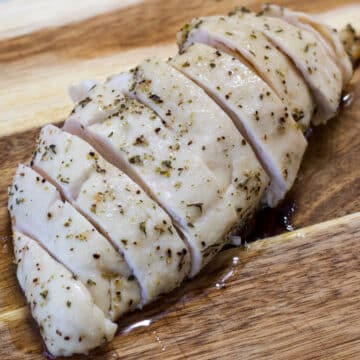 A sliced chicken breast on a wooden cutting board, you can see how juicy it is.