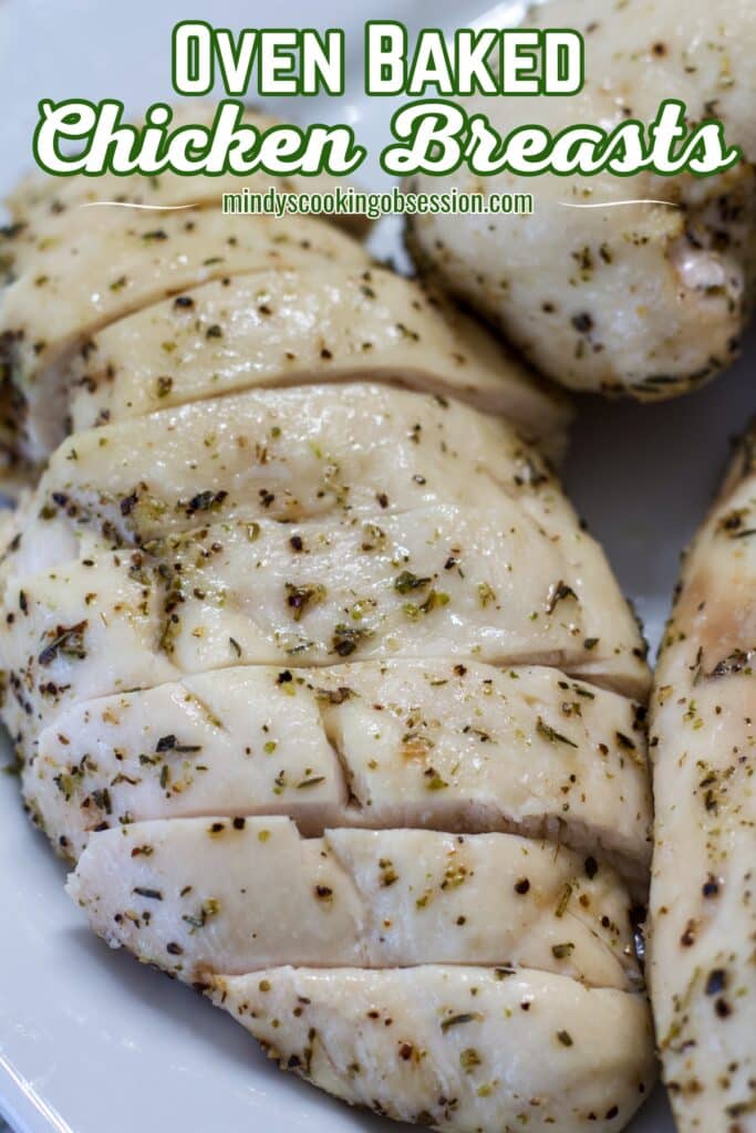 Close up of one chicken breast that has been sliced, there are uncut breasts next to it.