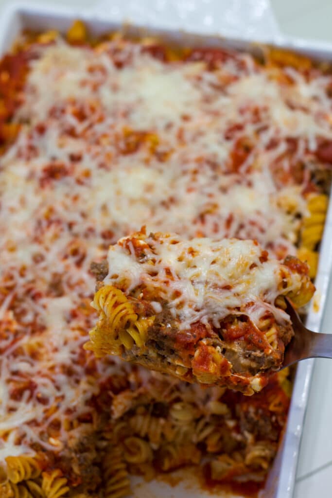 A large spoonful of Quick and Easy Homemade Lasagna Casserole in the foreground and the baking dish full in the background.