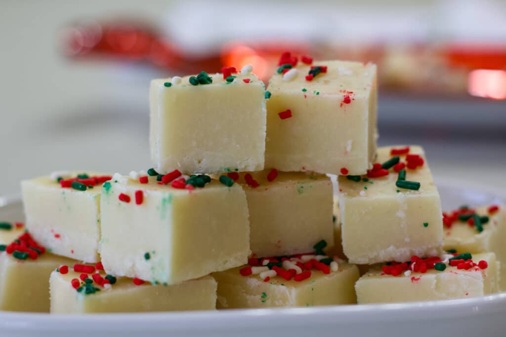 The side view of several pieces of Sugar Cookie Christmas Fudge on a plate.