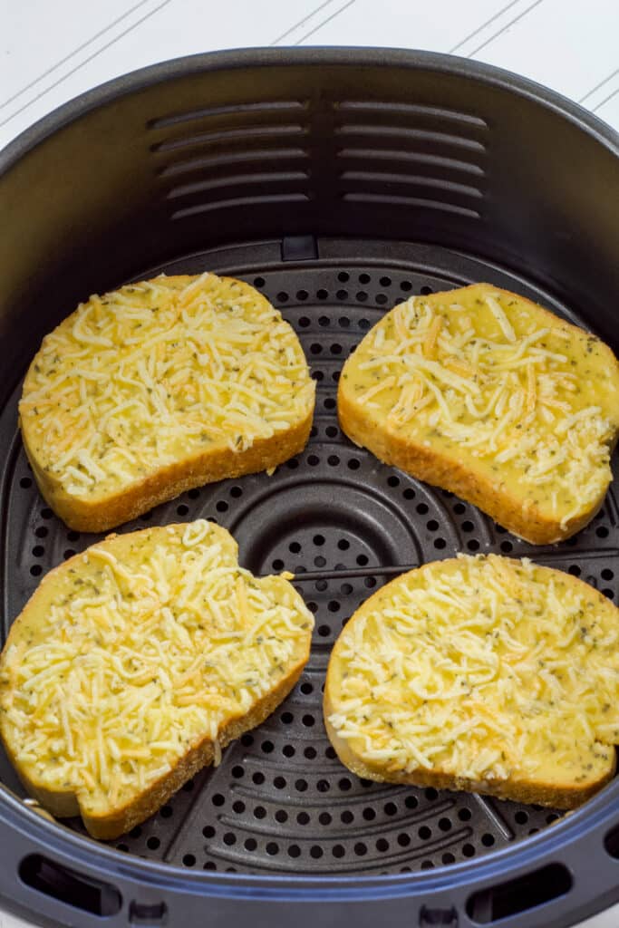 Four pieces of uncooked Texas toast in the air fryer basket.