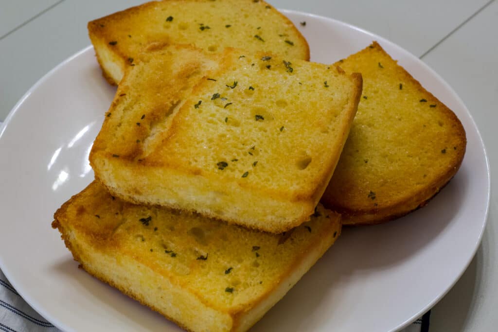 Four cooked pieces of air fried bread on a white plate.