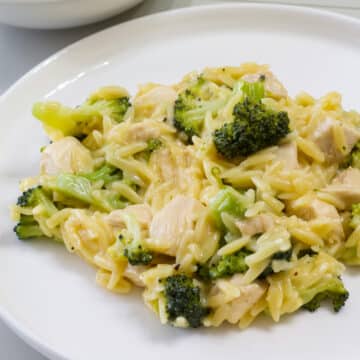A serving of Cheesy Chicken & Broccoli Orzo on a white plate.