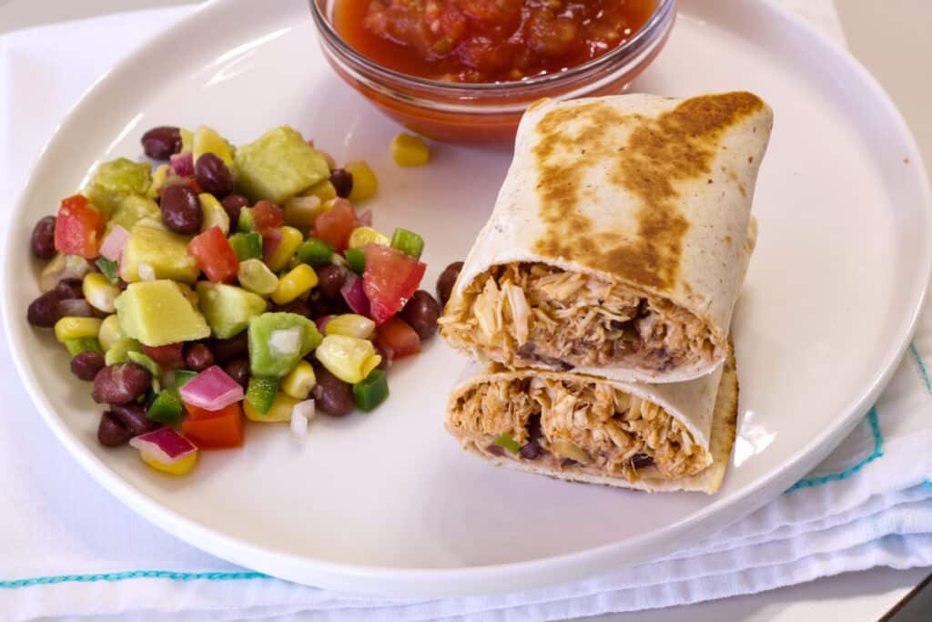 Overhead view of one burrito on a plate cut open so the insides are visible.