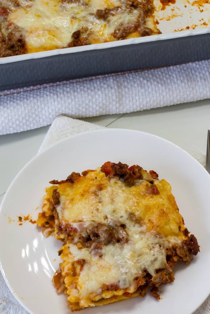 One serving of lazy lasagne on a white plate, the rest of the casserole is behind it.