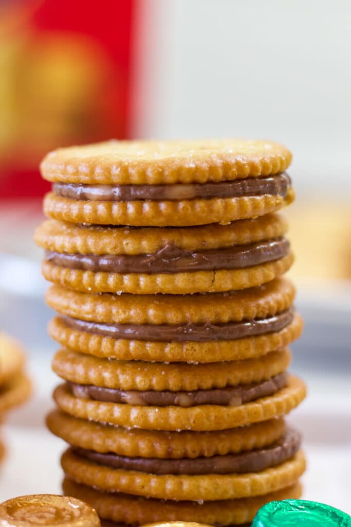 A stack of six Easy Rolo Stuffed Ritz Crackers Treats with some Rolo candies next to them.