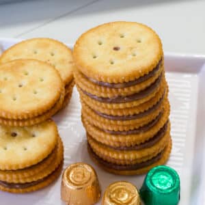A stack of six Easy Rolo Stuffed Ritz Crackers Treats and several more around them, there are 3 wrapped rolos too.