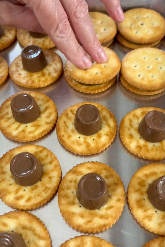 Several ritz with rolos on them and my fingers pressing the top cracker onto the softened rolo.