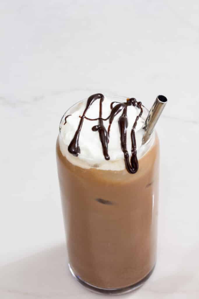 Overhead view of the tall glass of iced chocolate coffee topped with whipped cream and a drizzling of chocolate sauce.
