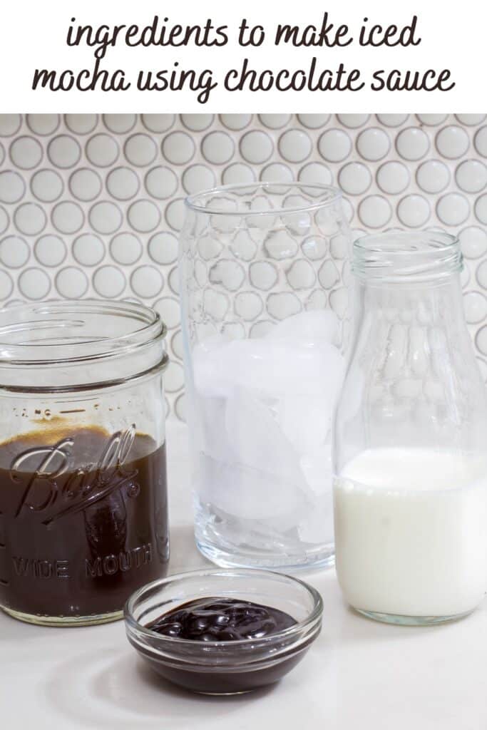 A mason jar with coffee, bottle of milk, cup of ice and small bowl full of chocolate sauce.