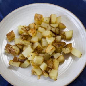 Overhead view of one serving of fried potatoes on a plate.