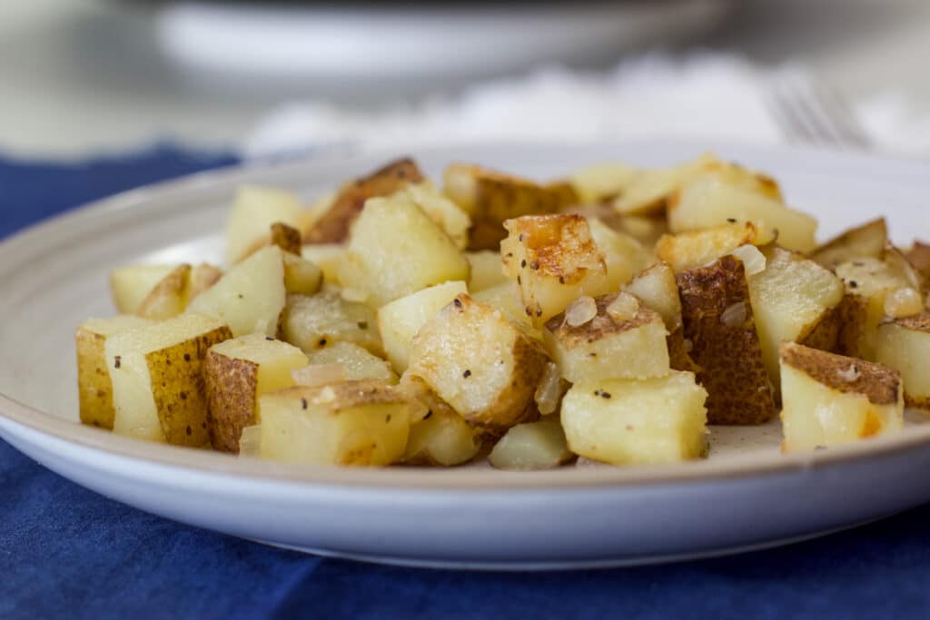 Side view of one serving of pan-fried potatoes on a plate.