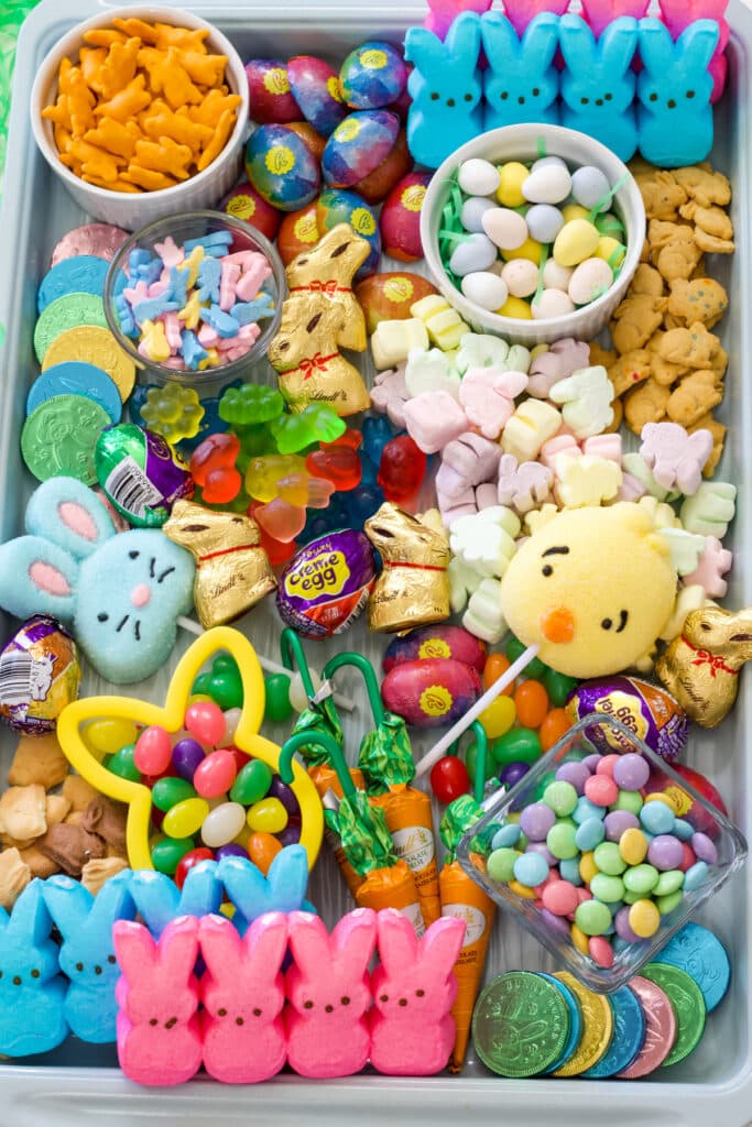 A light turquoise colored rimmed baking sheet filled with various types of Easter candy.
