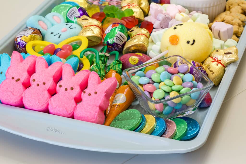 Side view of the bottom of the tray where you can see pastel candies and pink and blue peeps.