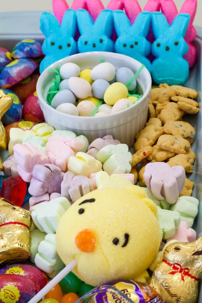 Close up of a chick shaped marshmallow pop with other candies in the background.