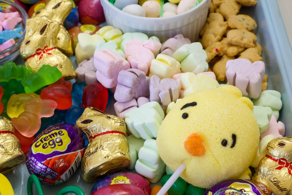 Many types of Easter candy on a tray, there are cadbury eggs, Lindt chocolate bunnies, and bunny shaped marshmallows.