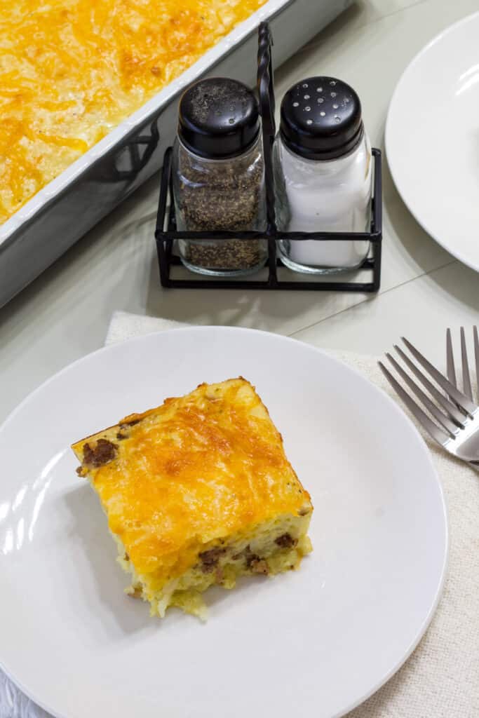 One serving of sausage breakfast casserole on a plate with salt and pepper shakers sitting next to it.