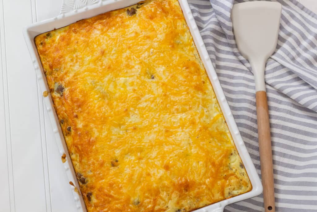 The whole baked breakfast casserole in the baking dish with a serving utensil sitting next to it.