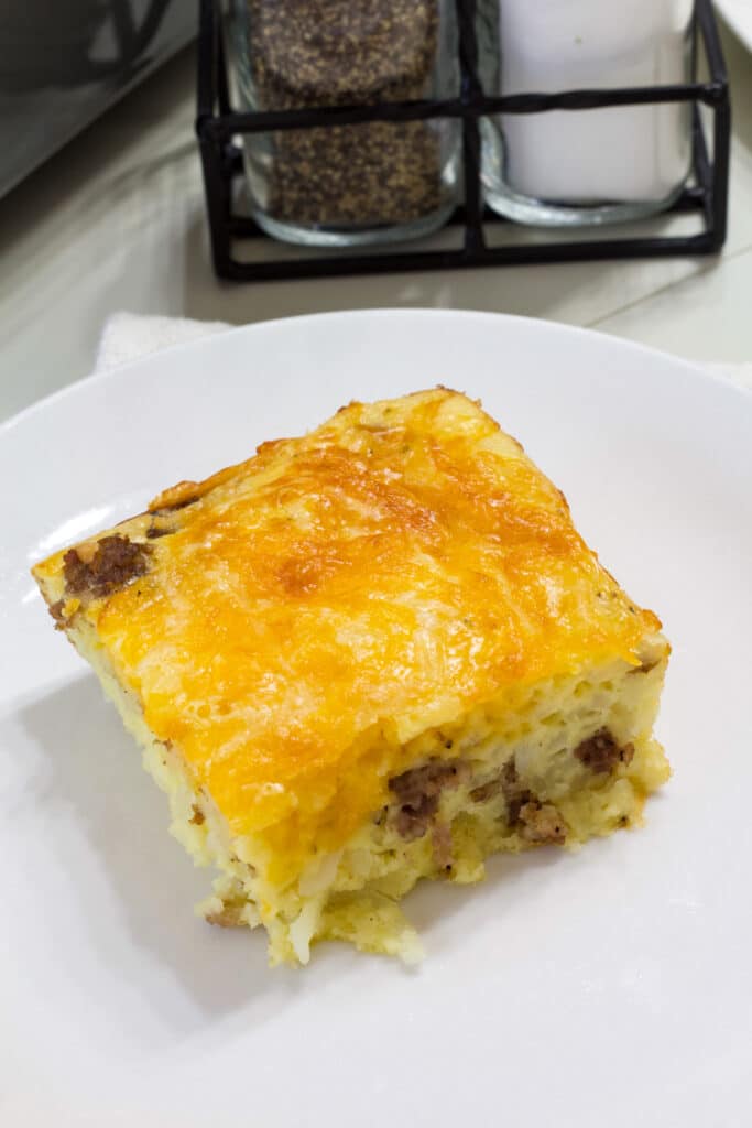 Close up view of one serving of Easy Bisquick Sausage Breakfast Casserole on a white plate.
