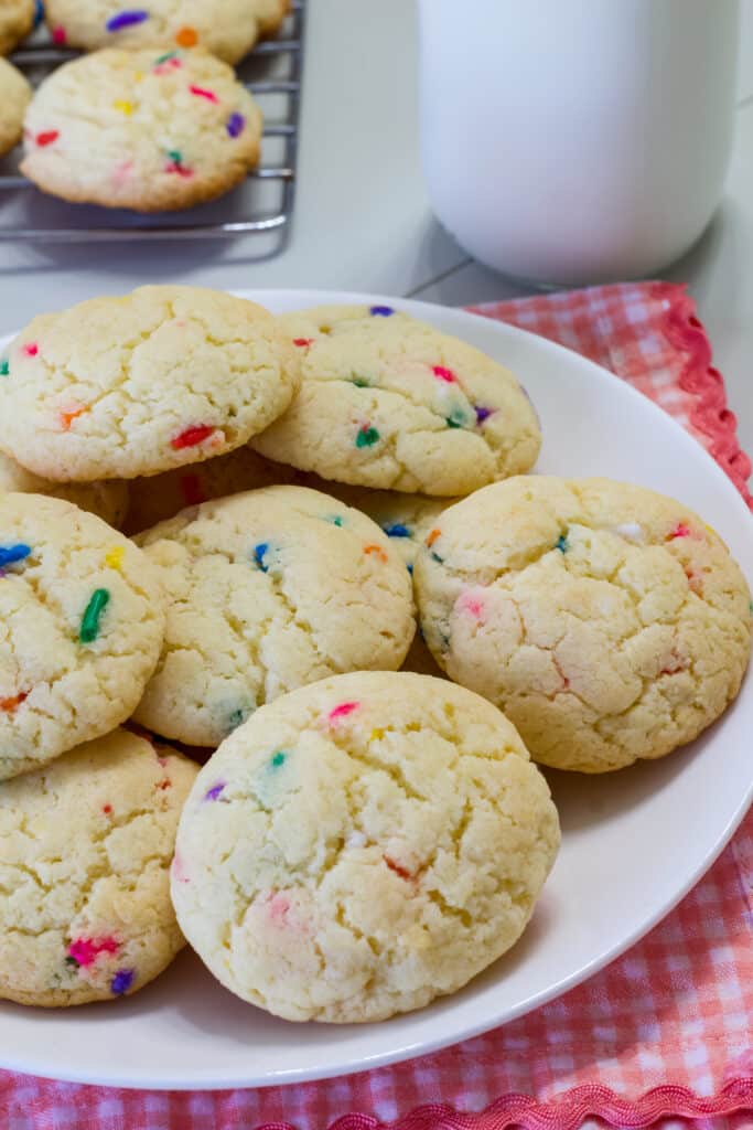 A plate full of baked Easy Funfetti Cookies on a pink and white checkered napkin.