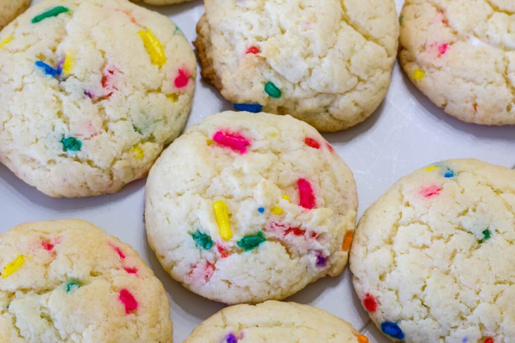 Several baked cookies on a white background, the rainbow sprinkles in them are visible.