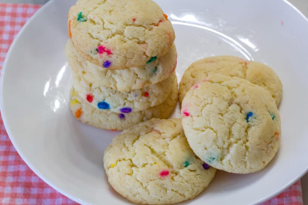 A stack of four cookies and three other cookies on a white plate.