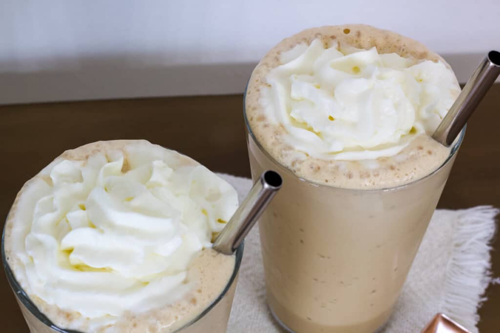 The top view of two glasses of vanilla frappuccino topped with whipped cream.