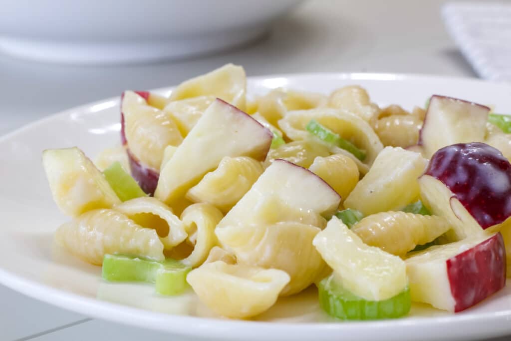 Side view of one serving of Waldorf Pasta Salad with Pineapple on a white plate.