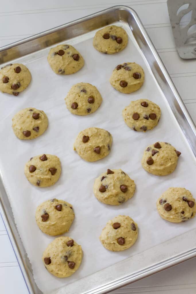 Fifteen baked Steel-Cut Oats Chocolate Chip Cookies on a parchment paper lined rimmed baking sheet.