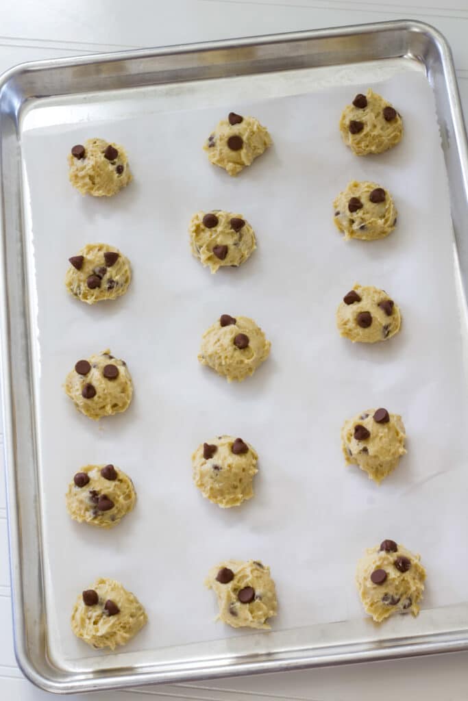 Fifteen unbaked cookies on a baking sheet lined with parchment paper.