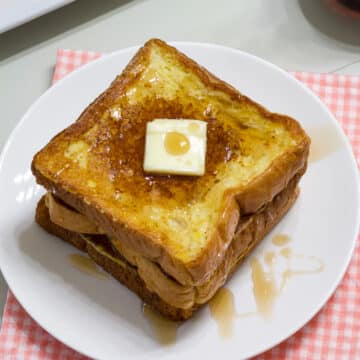 The feature image showing three slices of french toast with a pat of butter and maple syrup drizzled on them.